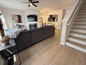 A modern living room with a sofa, a flat-screen TV, and a fireplace. - Spacious 4-bedroom townhome Cary/Morrisville area (Cary)