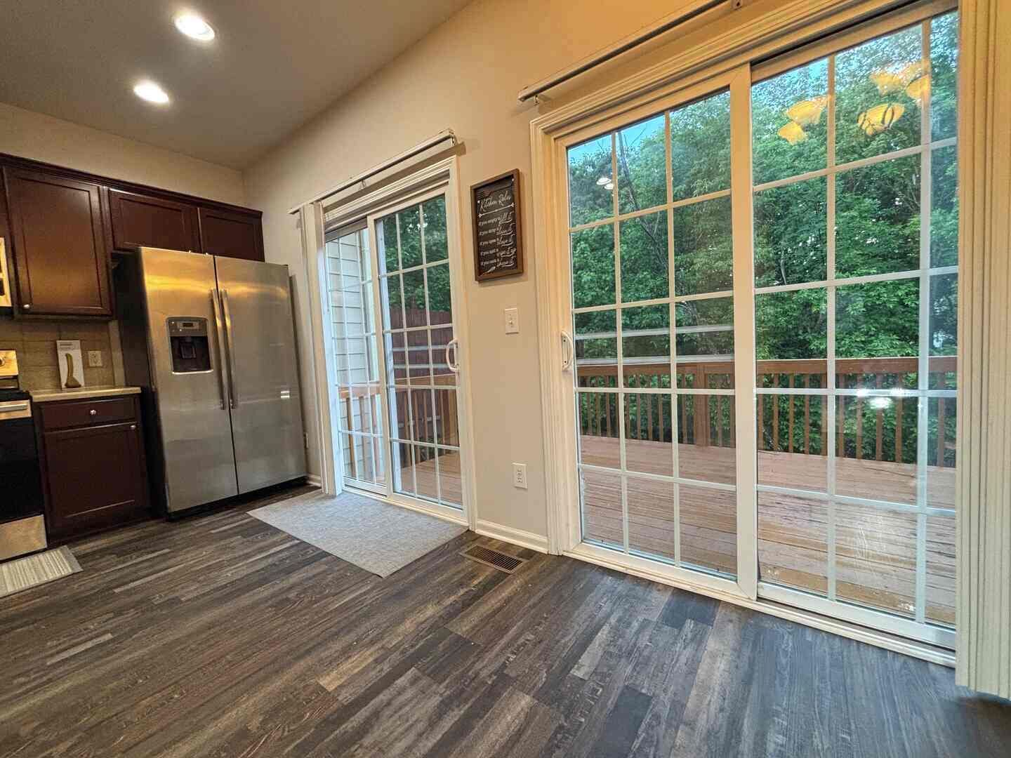 A kitchen with a stainless steel refrigerator, wooden cabinets, and a sliding glass door leading to a deck.