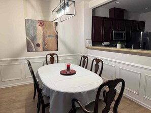 A dining area with a round table, six chairs, a white tablecloth, and a painting on the wall. - Spacious 4-bedroom townhome Cary/Morrisville area (Cary)