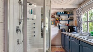 A modern bathroom with a glass-enclosed shower, a sink, and a window with a view of greenery.