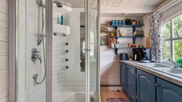 A modern bathroom with a glass-enclosed shower, a sink, and a window with a view of greenery.