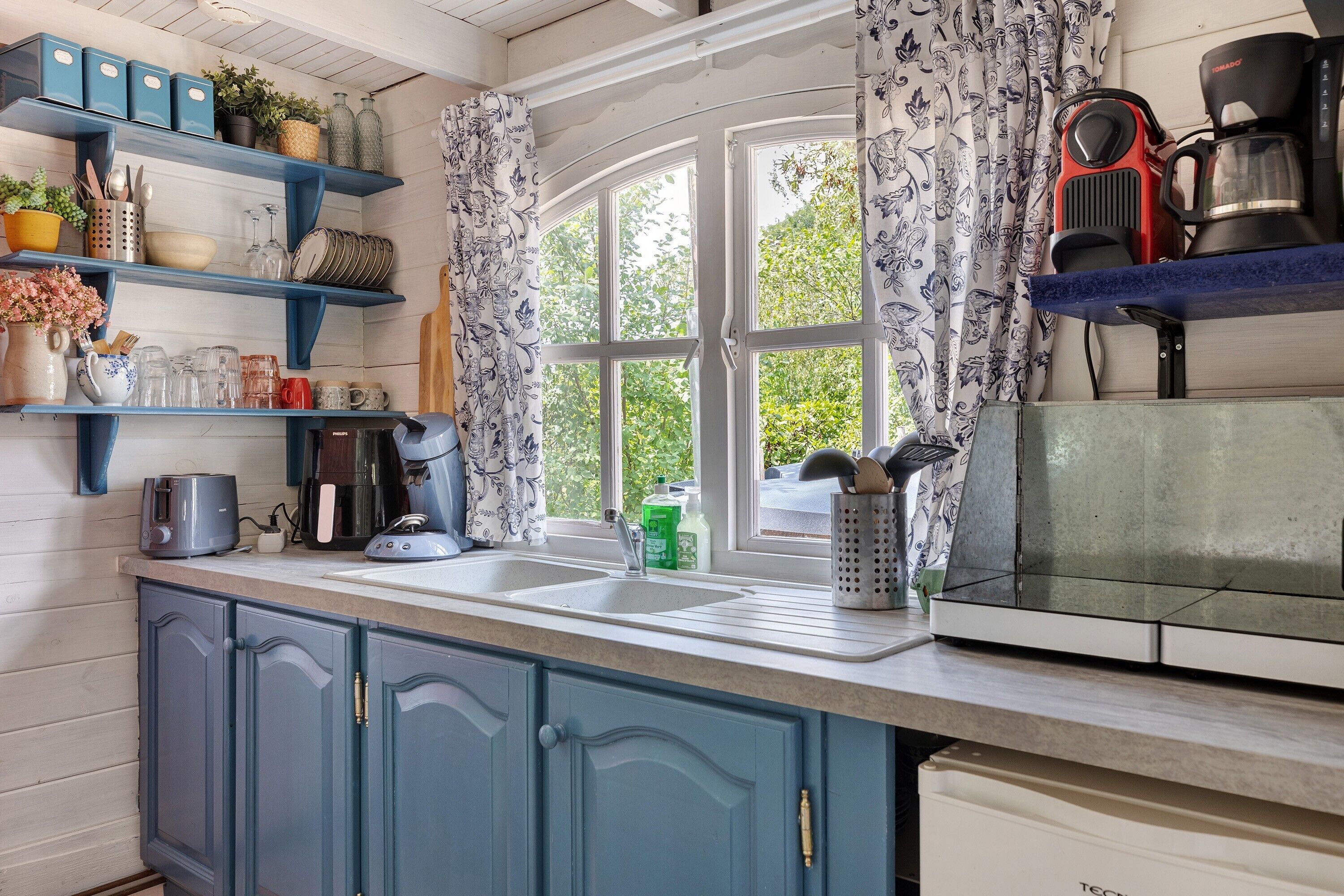 A kitchen with a window, a toaster, a coffee maker, and various kitchen utensils.