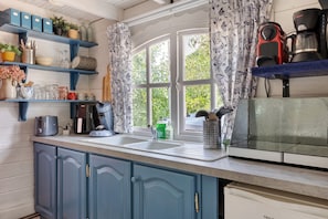 A kitchen with a window, a toaster, a coffee maker, and various kitchen utensils.