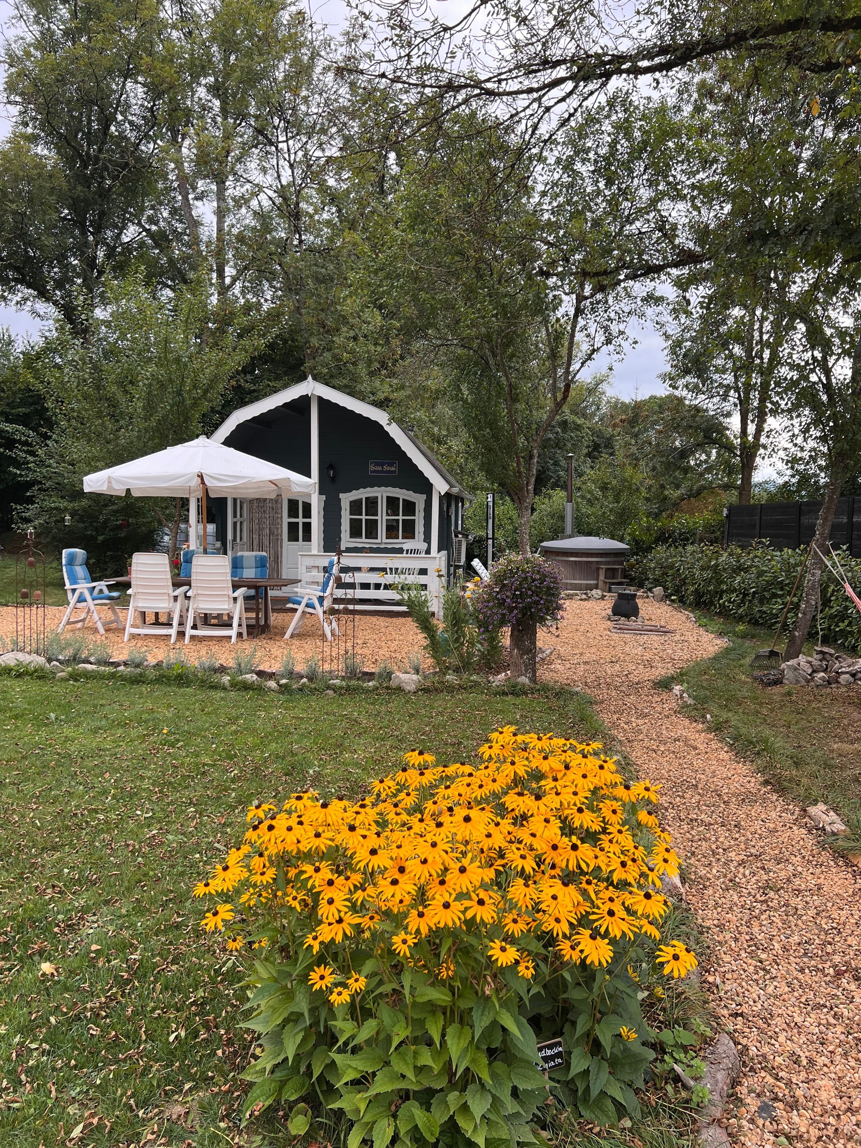 A house with a porch, outdoor seating, and a garden with yellow flowers.