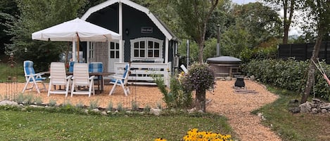 Ein Haus mit Veranda, Sitzgelegenheiten im Freien und einem Garten mit gelben Blumen.