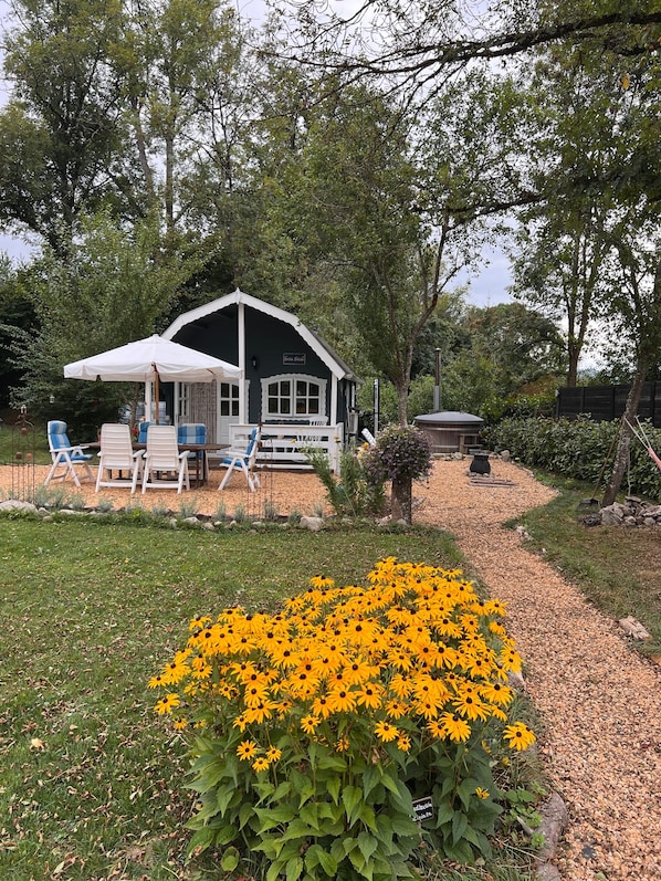 A house with a porch, outdoor seating, and a garden with yellow flowers.