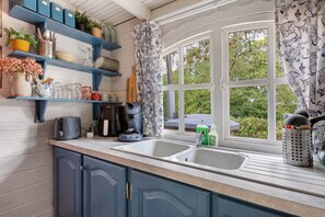 A kitchen with a built-in sink, blue cabinets, and a window with patterned curtains.