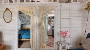 Et soveværelse med en seng, et natbord med en vase blomster og en garderobe.