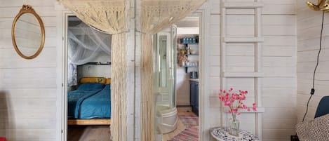 Un dormitorio con una cama, una mesita de noche con un florero y un armario.