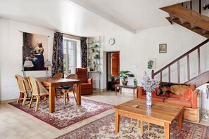 Una sala de estar con comedor, una escalera y vistas al exterior.