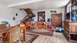 Ein geräumiges Wohnzimmer mit einer Holztreppe, einem großen Blumenbild und einem traditionellen Holzschrank.