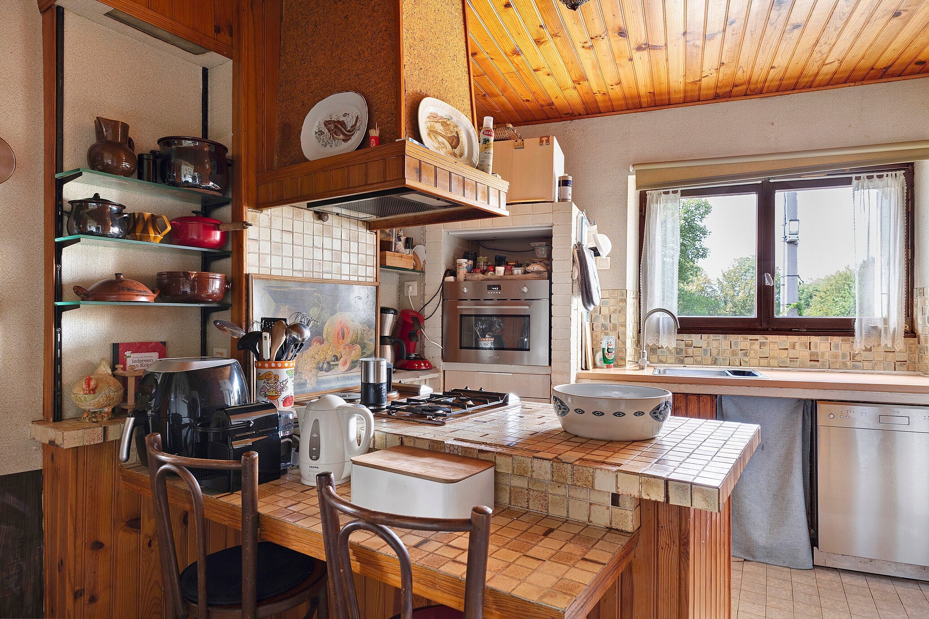Une cuisine avec des meubles en bois, une cuisinière, une machine à café et une fenêtre donnant sur un beau paysage.