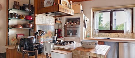 A kitchen with wooden cabinets, a stove, a coffee maker, and a window with a view.