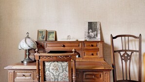 Ein Schreibtisch aus Holz mit Schubladen, einer Lampe und gerahmten Bildern.