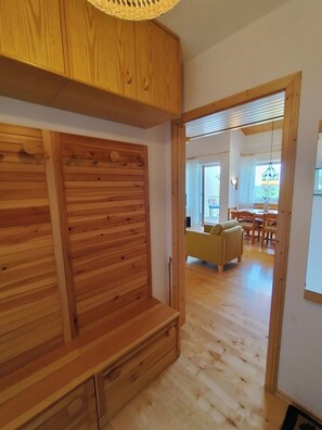 A wooden interior with a bench, a dining area with a table and chairs, and a view through an open door. - Black Forest Happiness - My SWH Schönwald (Schönwald im Schwarzwald)