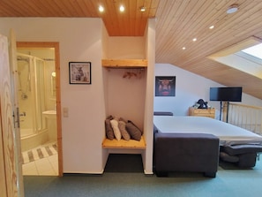 A bedroom with a bed, a bedside table, a TV, and a wooden shelf with pillows. - Black Forest Happiness - My SWH Schönwald (Schönwald im Schwarzwald)