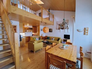 A spacious living area with a wooden staircase, a dining table, and a sofa. - Black Forest Happiness - My SWH Schönwald (Schönwald im Schwarzwald)