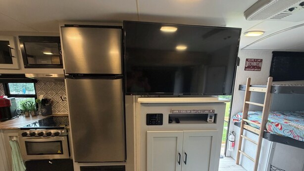 Cocina compacta equipada con refrigerador, horno, microondas y televisor.