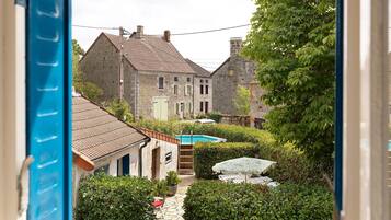 Ein Innenhof mit Swimmingpool, Steingebäuden und üppiger Bepflanzung.