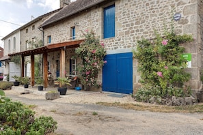 A stone building with a blue door and a telephone public sign.