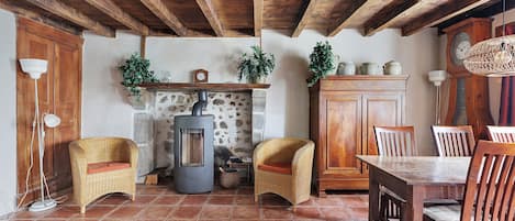 A rustic interior with a stone fireplace, wooden furniture, and a tiled floor.