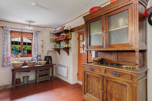 A traditional kitchen with wooden cabinets, a window with curtains, and a table with kitchenware.