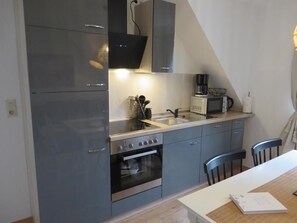 A compact kitchen with a built-in oven, microwave, and a coffee maker on the countertop. - NEW! Patis Vacation Rental on the North Sea (Moorweg)