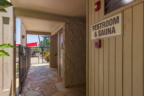 En sti med stenfliser, der fører hen til en dør med teksten 'RESTROOM & SAUNA'.