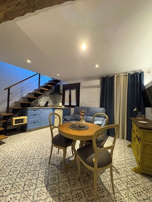 A compact living space with a dining area, a sofa, a staircase, and a kitchen area. - The Jewel of Setenil - Zafiro Cave House (Setenil de las Bodegas)
