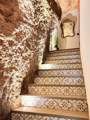 A staircase with patterned tiles and a rough stone wall. - The Jewel of Setenil - Zafiro Cave House (Setenil de las Bodegas)