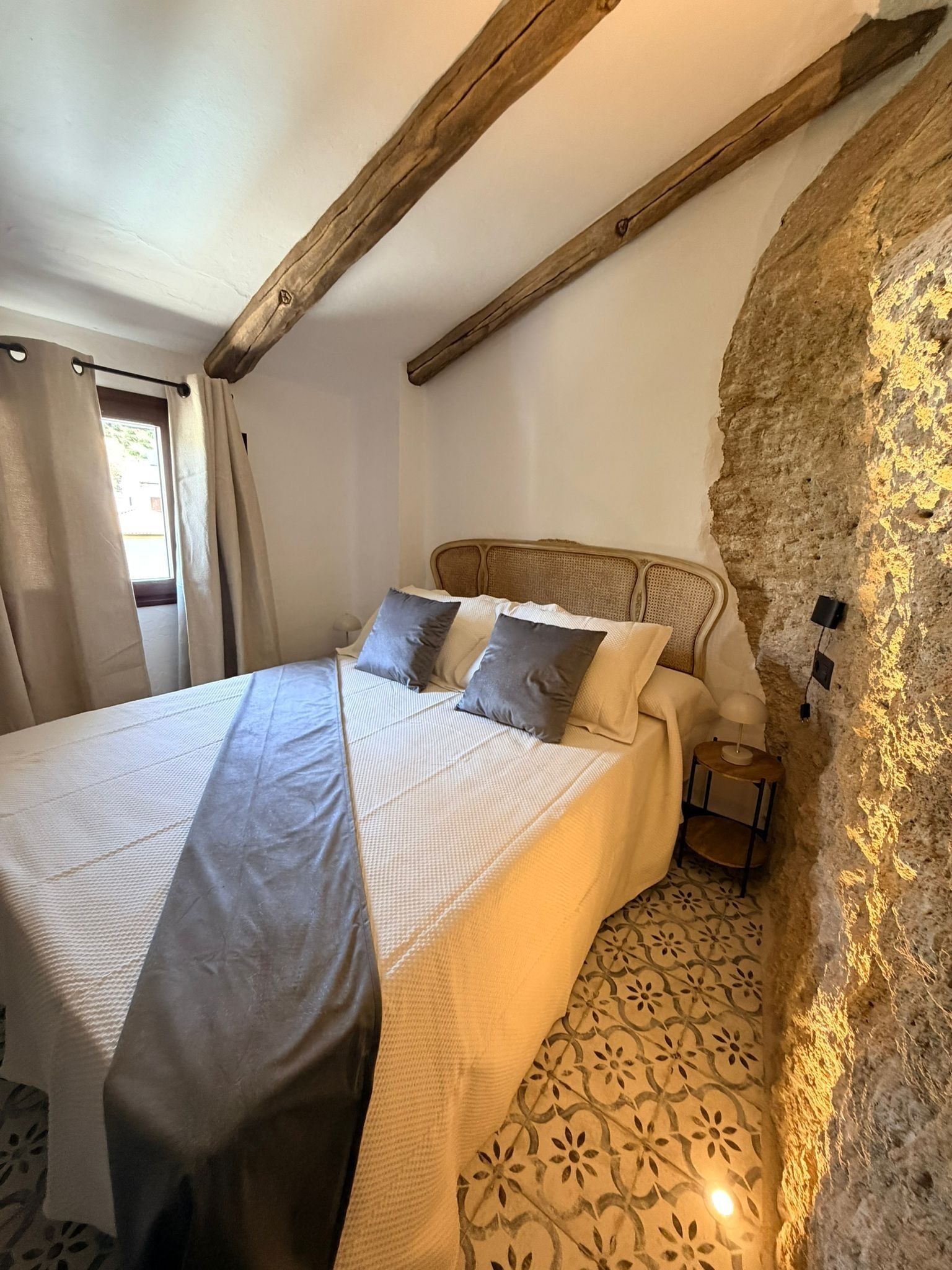 Une chambre à coucher avec un lit, des oreillers, une table de chevet et une lampe.