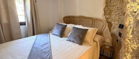 A bedroom with a bed, pillows, a nightstand, and a lamp.