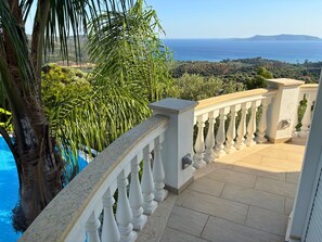 Ein Balkon mit Blick auf das Meer und die Hügel.