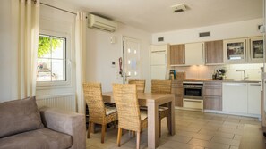 Eine moderne Küche mit Essbereich, inklusive Tisch und Stühlen, einem Backofen und einem Fenster mit Vorhängen.