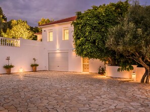 A house with a stone-paved driveway, a garage, and potted plants. - Villa Mandola, exclusive dream villa with pool and sea views in Finikounda (Grizokampos)