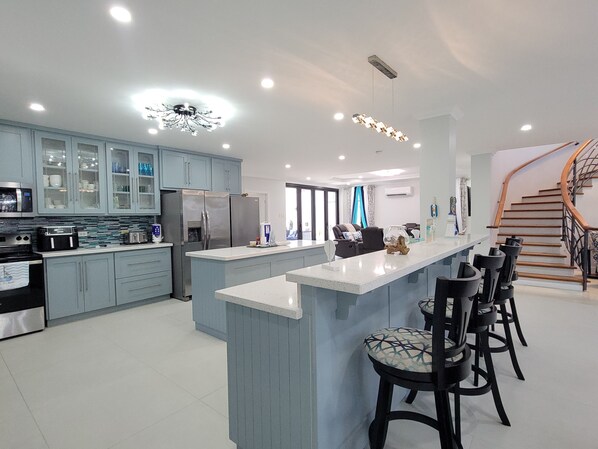A modern kitchen with a central island, bar stools, and a spiral staircase.