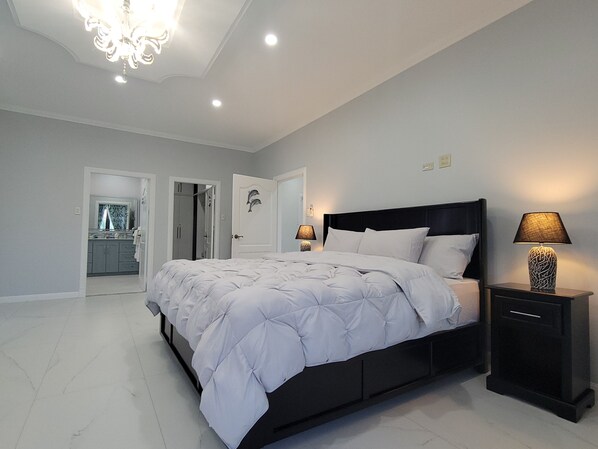 A bedroom with a bed, bedside tables, and a chandelier.