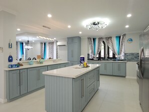 Una cocina moderna con gabinetes grises, una isla central y un refrigerador de acero inoxidable.