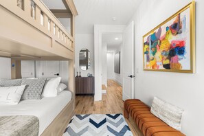 A modern hotel room with a bunk bed, a sofa, a colorful abstract painting, and a wooden floor. - Ovation @ The New Cumberland (Nashville)