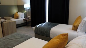 Una habitación de hotel con dos camas, un escritorio y una mesita de noche.
