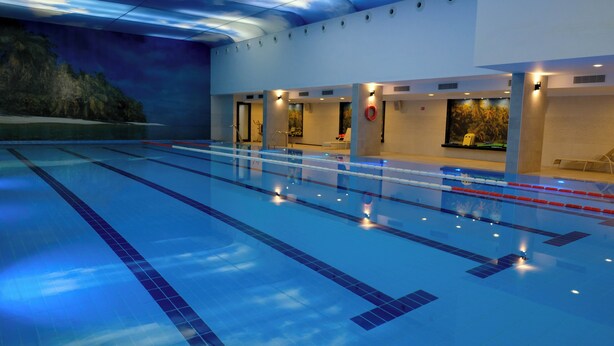 Una piscina interior con carriles, un puesto de socorrista y un mural en la pared.