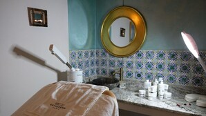 Un baño con toalla, lavamanos, artículos de aseo e espejo.