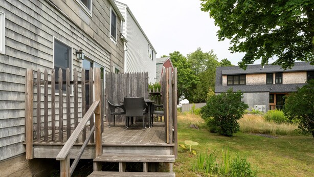 A wooden deck with outdoor furniture, a wooden fence, and a grassy yard with a tree. - Spacious Harbor Retreat | Easy Access to Downtown (Mount Desert)