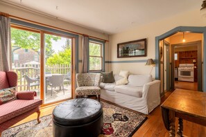 A cozy living room with a sofa, armchair, ottoman, and a dining table.