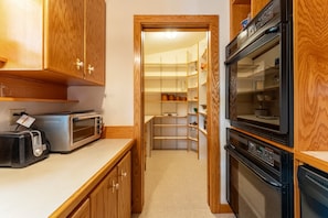 Eine Küche mit Holzausstattung, einem Toaster, einer Mikrowelle und einem schwarzen Backofen.