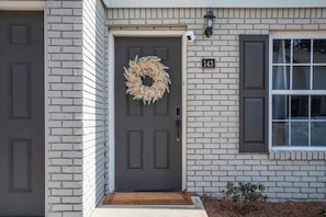 Une maison avec une porte d’entrée sombre, une couronne décorative et une boîte aux lettres.