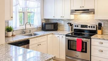 A modern kitchen with white cabinets, a stainless steel stove, a microwave, and a dishwasher.