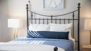 A bed with a metal frame, white bedding, and a blue quilt. There are two bedside lamps and a wall-mounted artwork above the bed. - The Redbird, Walk to Square, VelvetDitchVillas (Oxford)