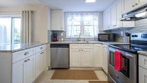 A modern kitchen with white cabinetry, stainless steel appliances, and a window with sheer curtains. - The Redbird, Walk to Square, VelvetDitchVillas (Oxford)