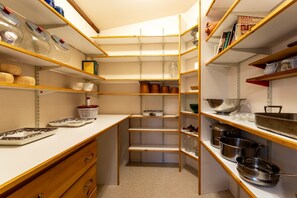 A kitchen with wooden shelves, a white countertop, and various kitchenware. - Full Lovely Home Walking Distance to Town & Harbor (Mount Desert)